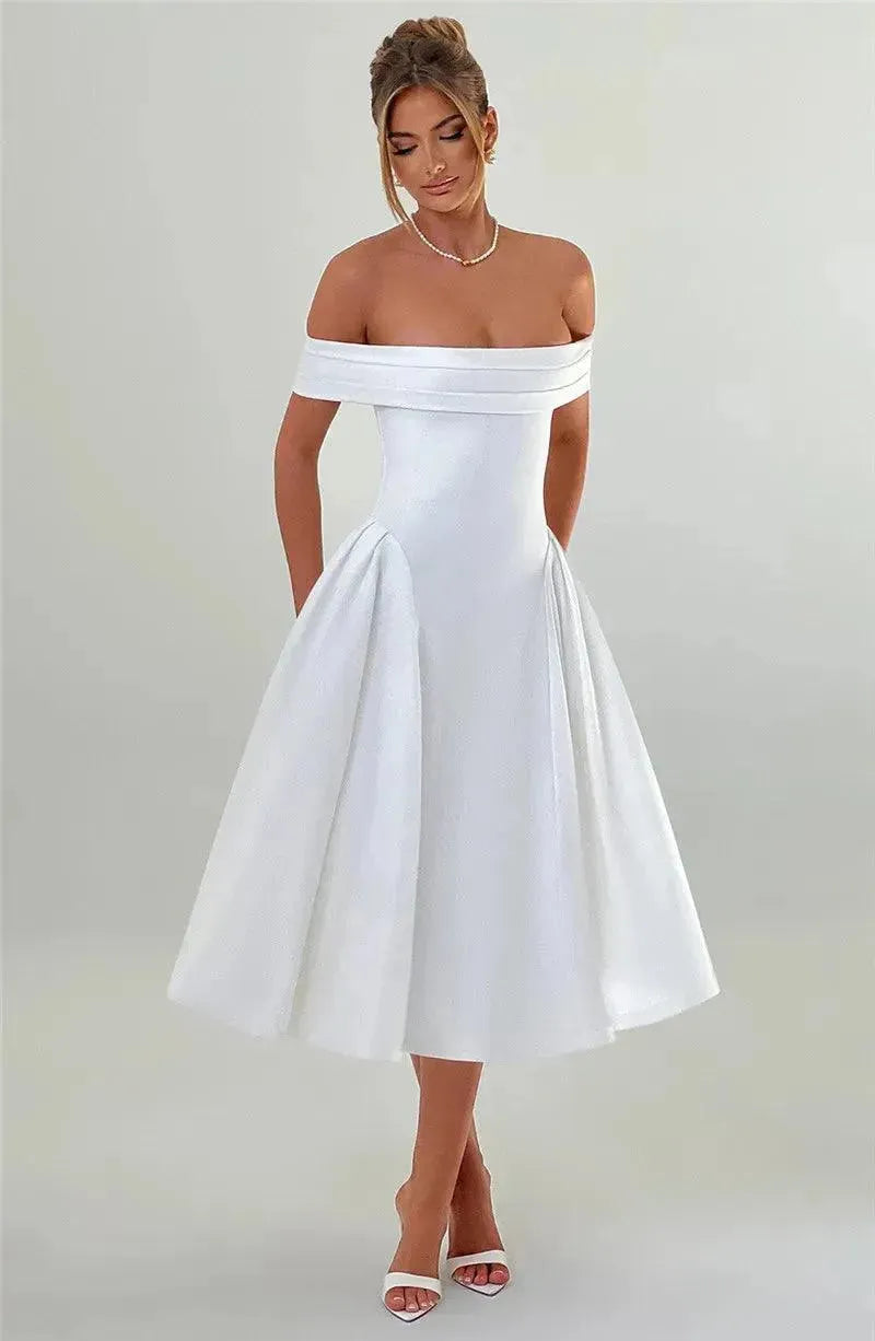 Woman wearing a white off-shoulder dress against a plain background