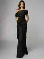 A model wearing a black, floor-length, one-shoulder maxi dress with a V-neck neckline and sleeveless design.