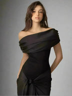 Woman wearing a black one-shoulder dress against a gray background