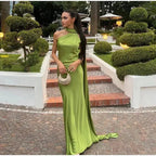 Woman in a green dress standing on a stone path with garden decorations.