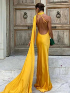 Person wearing a yellow evening gown in front of a wooden door.