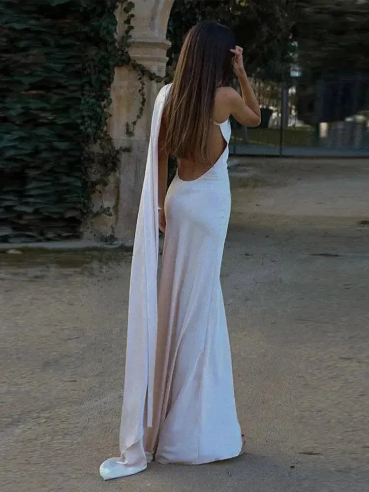 Woman in a long white dress walking in a garden setting.