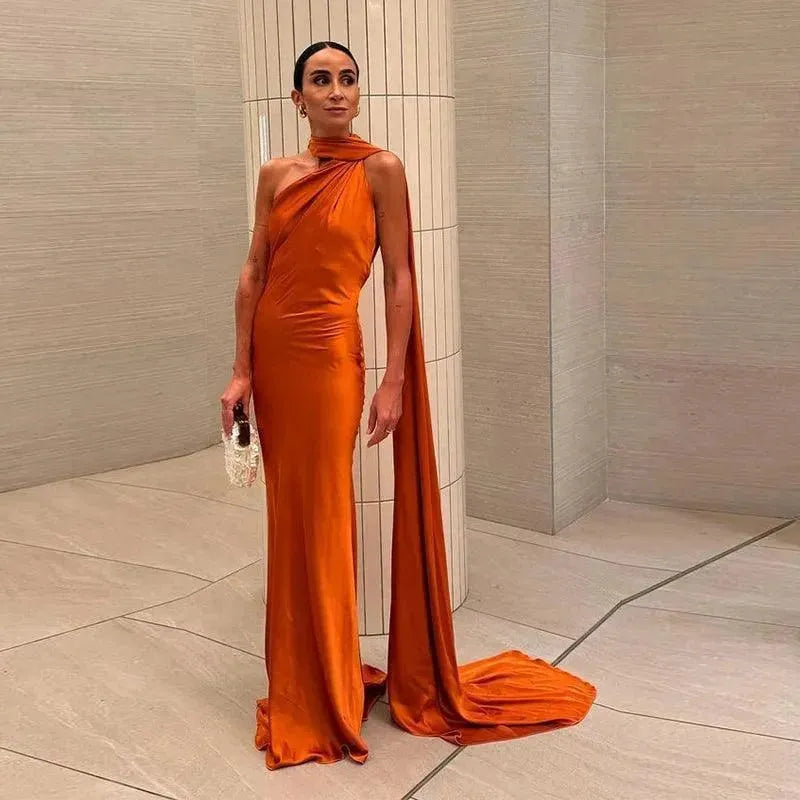 Woman in an orange evening gown standing in a neutral room.