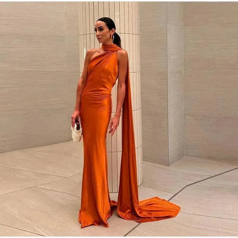 Woman in an orange evening gown standing against a neutral background.