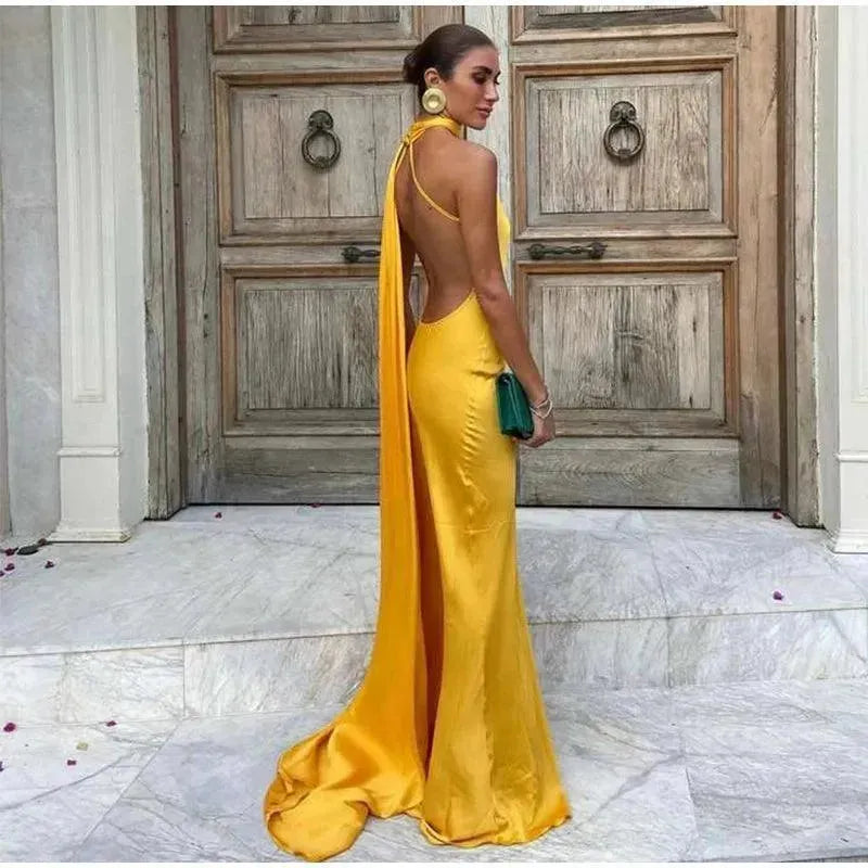 Woman in a yellow evening gown standing in front of a wooden door.