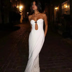 Woman in a white dress standing on a cobblestone street at night.
