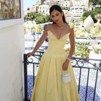 Woman in a yellow dress standing on a balcony with a cityscape in the background.