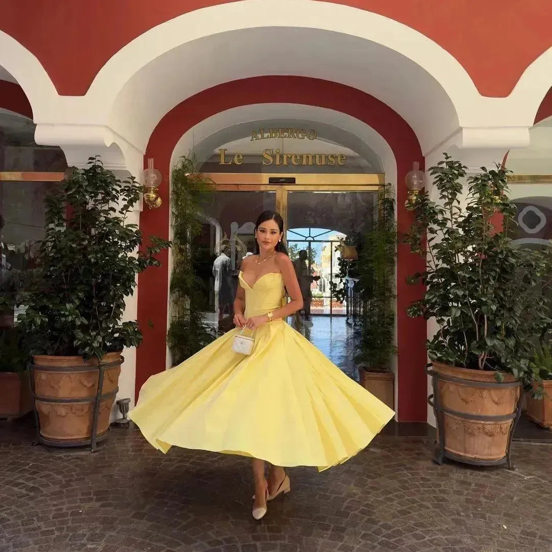 Woman in a yellow dress standing in an archway with plants.